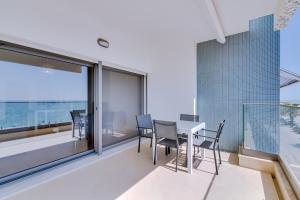 una sala da pranzo con tavolo e sedie sul balcone di Brisa do Mar 2Br - Sea front - Luxury apartment a Quarteira