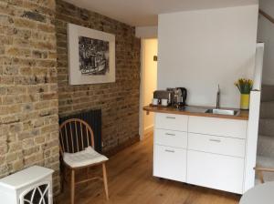 a kitchen with a brick wall and a table and chair at Passengers House in Whitstable
