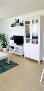 ein Wohnzimmer mit einem TV und einem weißen Schrank in der Unterkunft CHEZ JOGO in Chamousset