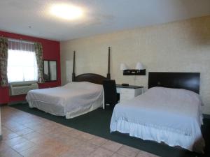 a hotel room with two beds and a desk at The Garden Villas Hotel in Valdosta