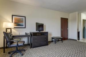 una camera d'albergo con scrivania, TV e sedia di Holiday Inn Poplar Bluff, an IHG Hotel a Poplar Bluff