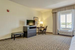 Cette chambre comprend un lit, un bureau et une télévision. dans l'établissement Holiday Inn Poplar Bluff, an IHG Hotel, à Poplar Bluff