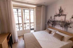 Un dormitorio con una gran cama blanca y una ventana en Plaza Mayor Suites & Apartments, en Madrid