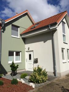 uma casa verde e branca com um telhado vermelho em Ferienhaus am Yachthafen em Greifswald