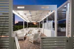 a patio with white chairs and tables under a pergola at Hotel Luna Lido in Torre San Giovanni Ugento