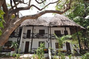 mały biały dom z dachem krytym strzechą w obiekcie Baobab Sea Lodge w mieście Kilifi