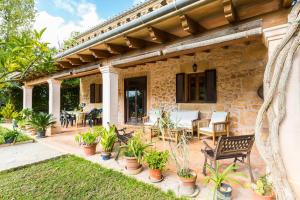 a stone house with a patio with chairs and plants at Villa Agina in Algaida