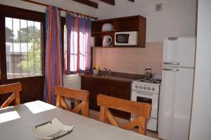 a kitchen with a white refrigerator and a table with chairs at Brisa Apart Valeria del Mar in Valeria del Mar