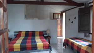 a bedroom with a bed and a tv on the wall at Casa Colibri in Santa Cruz Cabrália