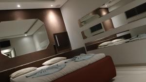 a bedroom with two beds and a mirror at Delirio Moteis Pousada in Dourados