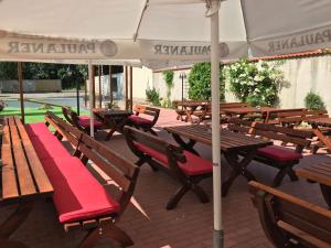 a group of wooden tables and benches with an umbrella at Hotel Goldenes Schiff in Grimma