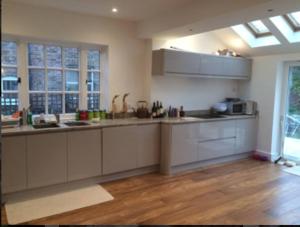 a kitchen with white cabinets and a wooden floor at Flora Cottage in Guildford