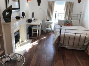 a room with a fireplace and a bed and a desk at Flora Cottage in Guildford