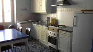a kitchen with white cabinets and a stove and a table at Gite Au Coeur De Volnay in Beaune
