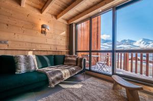 een woonkamer met een groene bank en een balkon bij Val Thorens - Cosy Duplex avec Vue Silveralp 338 in Val Thorens