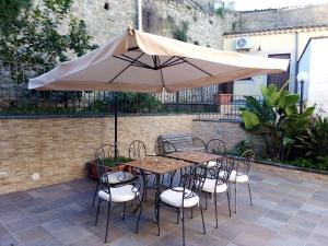 stół i krzesła pod parasolem na patio w obiekcie Bed & Breakfast Via Venezia w mieście Regalbuto