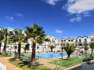 a resort with a swimming pool and palm trees at Estupendo Apartamento Gaudia in Caleta De Fuste