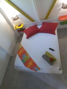 a white bed with red pillows and a tie at Fetay Jaune in Baie-Mahault