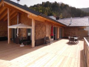 una terraza de madera con mesa y sombrilla en Penthouse Alpine Living direkt an der Skipiste by Schladmingurlaub, en Haus im Ennstal