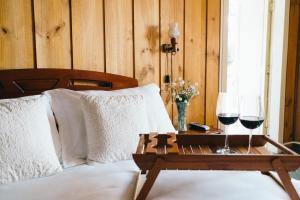 a bed with a table with two glasses of wine at Hosteria de la Colina in Villarrica