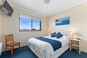 Un dormitorio con una cama y una silla y una ventana. en Allambi Holiday Apartments, en Lakes Entrance 28 fotos más