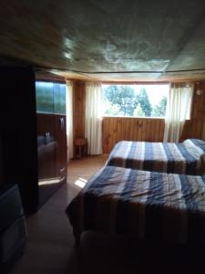a bedroom with a bed and a large window at La Lomita Guadal in Puerto Guadal