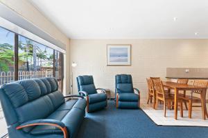 a living room with blue furniture and a dining room at Allambi Holiday Apartments in Lakes Entrance