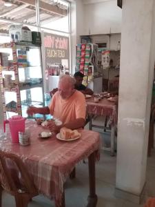 a man sitting at a table with a plate of food at Wick's Apartment in Hikkaduwa