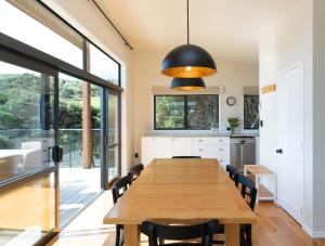 uma cozinha e sala de jantar com uma mesa de madeira e cadeiras em The Cottage at Te Whau Retreat em Te Whau Bay