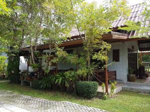 a house with trees and plants in front of it at Asiana House in Khao Lak