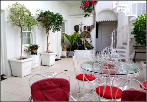 een eetkamer met een glazen tafel en rode stoelen bij Stonehurst Guest House in Kaapstad