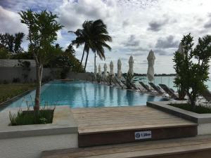 a swimming pool with chairs and umbrellas at OBiches Luxury Beachfront Apartment Trou-aux-Biches in Trou aux Biches