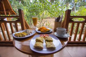 a table with two plates of food and a glass of orange juice at Nusa Penida Pudak Nature Bungalow in Nusa Penida