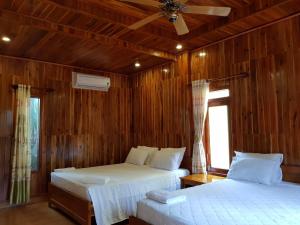 two beds in a room with wooden walls at Free Beach Resort in Phú Quốc