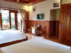 a bedroom with two beds and a tv on the wall at Free Beach Resort in Phú Quốc