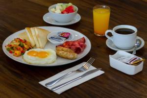a plate of breakfast food with eggs and toast and coffee at PrimeBiz Hotel Kuta in Kuta