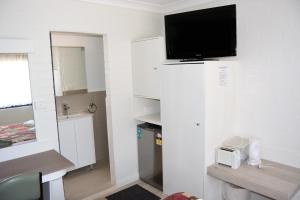 een kleine kamer met een tv aan de muur bij Civic Motor Inn in Cowra