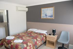 Habitación de hotel con cama y silla en Civic Motor Inn, en Cowra