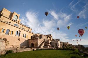a group of hot air balloons flying over a building at Kistar Cave Hotel in Uçhisar