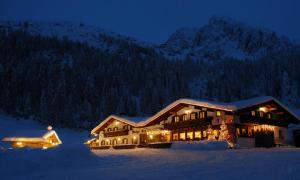a large lodge in the snow at night at Malga Ces in San Martino di Castrozza