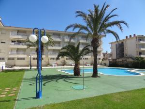 a swimming pool with palm trees in front of a building at Apartamentos Blaumar in L'Estartit
