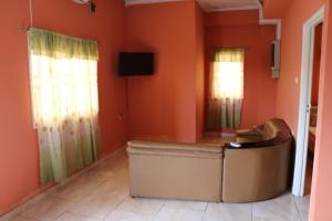 a living room with orange walls and a couch at Happy Holidays Style Residences in Paramaribo