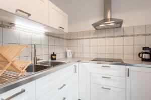 - une cuisine avec des placards blancs et un évier dans l'établissement Appartement cœur de ville - Wifi - Lave-sèche linge, à Pau