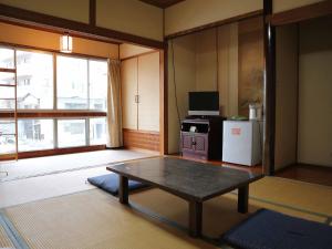 a living room with a table and a refrigerator at Kimatsu Ryokan in Hiroshima