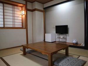 a living room with a wooden table and a television at Kimatsu Ryokan in Hiroshima