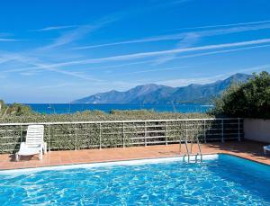 a swimming pool with a chair and a view of the ocean at Résidence Suarella in Saint-Florent