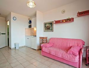 a living room with a pink couch and a kitchen at Résidence Suarella in Saint-Florent