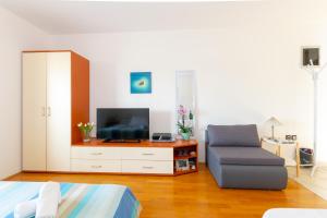 a bedroom with a bed and a chair and a television at Apartment IRENA with Bikes included in Pula