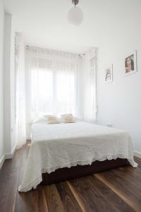 バレンシアにあるCool Loft Malvarrosa Beachの白いベッドルーム(白いシーツと窓付きのベッド付)
