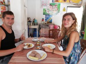 un homme et une femme assis à une table avec de la nourriture dans l'établissement Wick's Apartment, à Hikkaduwa